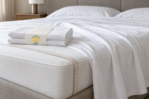 Folded white sheets with a Casa paper band on a bed beside a measuring tape around the mattress edge.