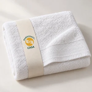 Folded white hotel bath towel with a woven border and removable Casa paper band.