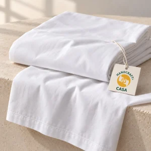 Folded white percale hotel bed sheet with a removable Casa presentation tag.