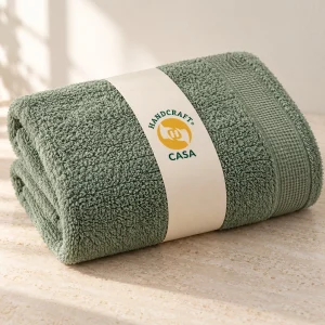 Folded green terry bath towel with a removable Casa paper band.
