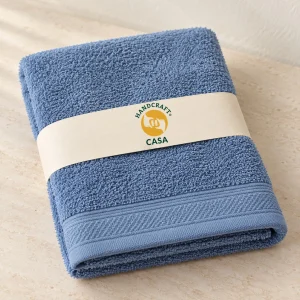 Folded blue terry hand towel with a removable Casa paper band.