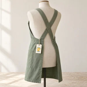 Green cross-back apron shown from behind on a dress form with a removable Casa paper tag.