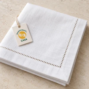 Folded white hemstitched cotton napkin with a removable Casa presentation tag.