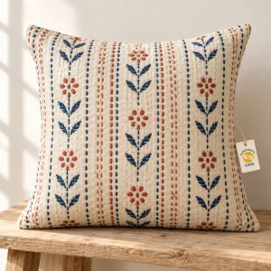 Cream cushion cover with blue and rust floral and stitched-row pattern, with a removable Casa paper tag.