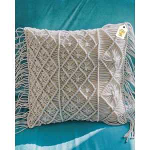 Cream cushion cover with raised knotted patterns and long side fringe on a teal seat.