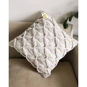 Cream cushion with raised diamond outlines and curved cord details on a beige chair.
