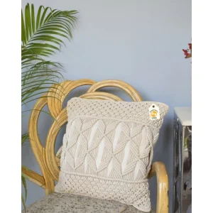 Cream cushion cover with raised diamond and banded geometric texture on a rattan chair.