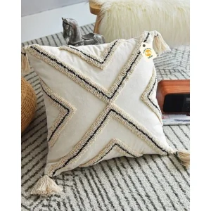 Cream cushion cover with black-trimmed raised zigzag patterns and corner tassels.