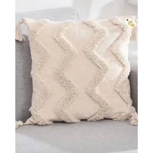 Cream cushion cover with raised wavy zigzag texture and corner tassels on a grey seat.