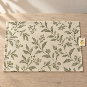 Sage botanical printed cotton placemat on a wooden table with a removable Casa paper tag.