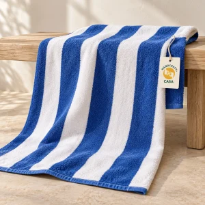 Blue and white striped pool towel draped over a wooden rail with a removable Casa tag.