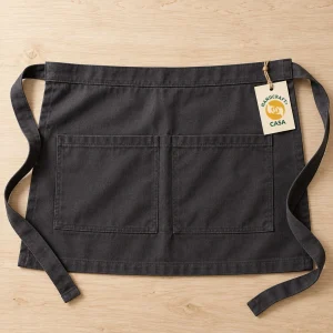 Dark waist apron laid flat with waist ties and a removable Casa paper tag.
