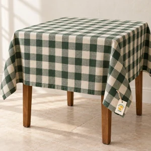 Green and ivory woven check tablecloth draped over a table with a removable Casa paper tag.
